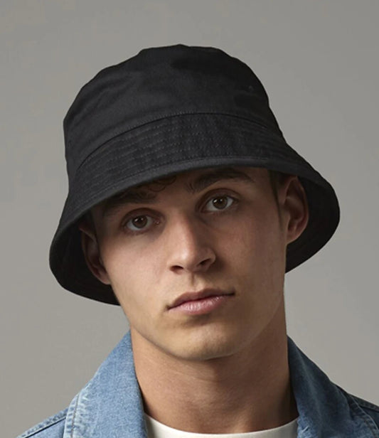 Person wearing a black bucket hat against a gray background