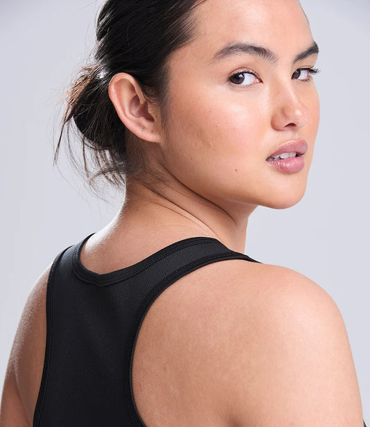 Woman wearing a black tank top against a plain background