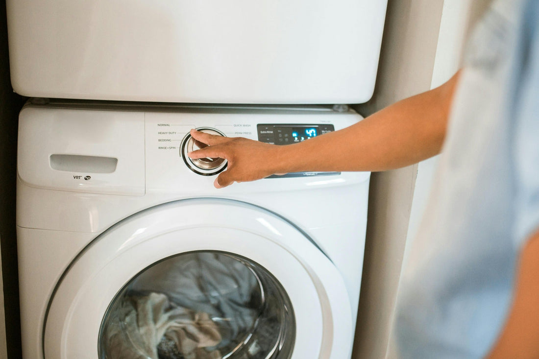 Person selecting wash cycle on modern washing machine control dial