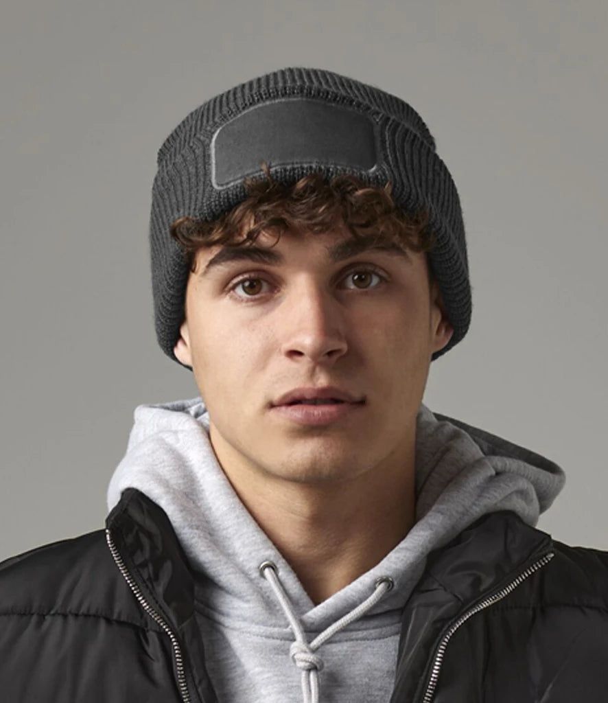 Person wearing a gray beanie and black jacket with a gray background