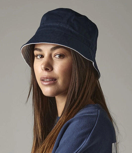Woman wearing a navy bucket hat against a plain background