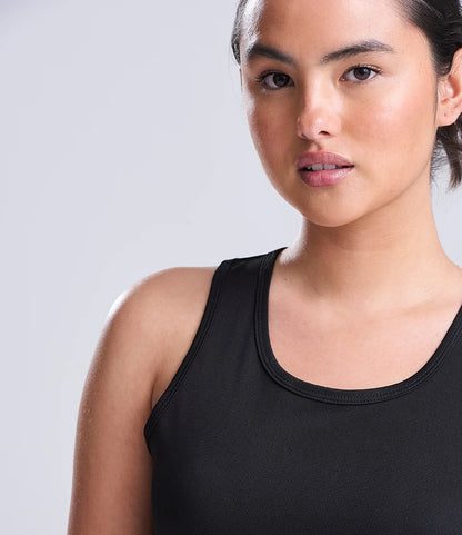 Woman wearing a black tank top against a light gray background