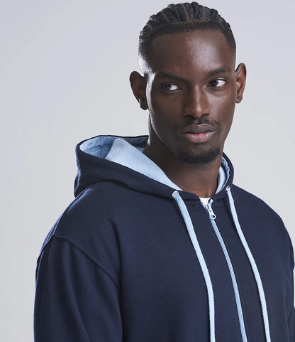 Man wearing a navy blue hoodie with a light blue lining on a plain background
