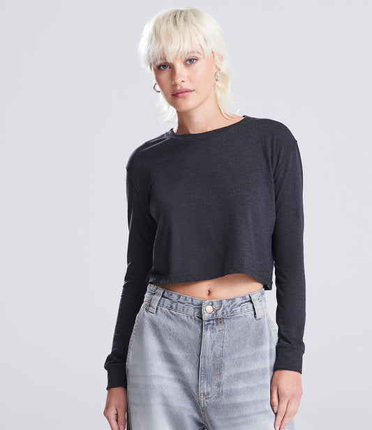 Person wearing a dark long-sleeve crop top and light gray jeans on a plain background
