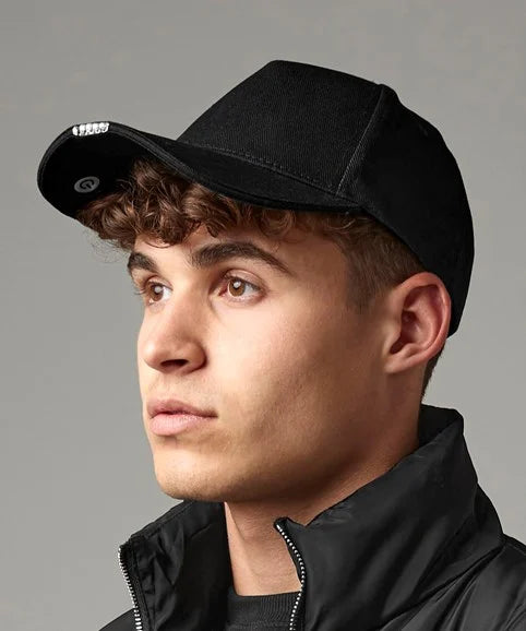 Person wearing a black cap with light in brim and black jacket against a gray background